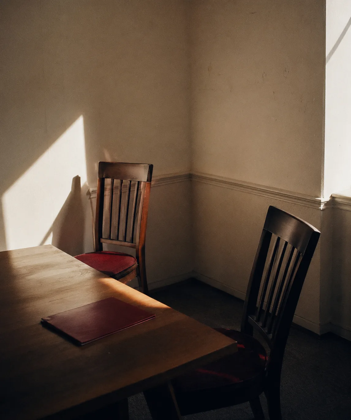 Two chairs at the end of a meeting-room table, nobody in them